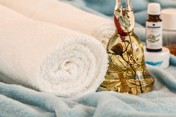 Two white towels next to a bottle of beauty oil