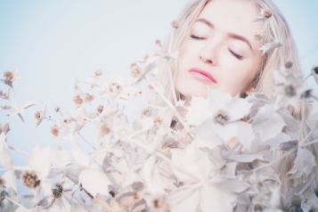 A woman with white hair covered in white leaves