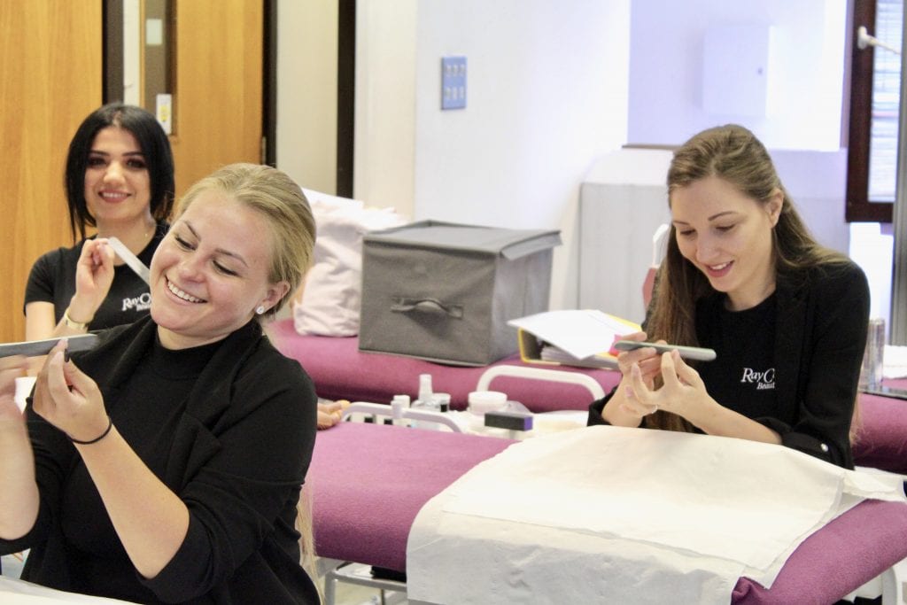 Three students at Ray Cochrane Beauty School nail filing